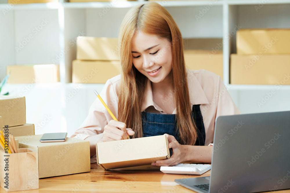 Online small business owner writing address on parcel box.