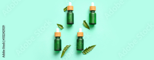 Bottles of cosmetic serum and fern leaves on color background © Pixel-Shot