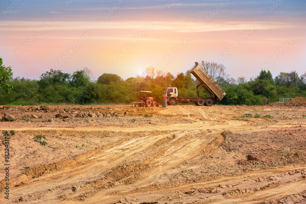 Fototapeta premium A truck is moving into sand at a ground leveling construction site., land plot for housing construction project with car tire print in rural area Land for sales landscape concept.