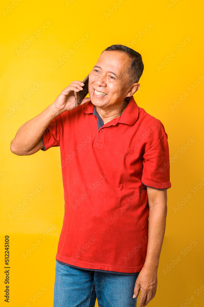 Portrait of happy Asian senior man talking on phone and smiling isolated over yellow background. Portrait of happy Asian senior man talking on phone and smiling isolated over yellow background.