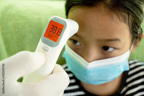 Hand using clinical thermometer to a girl and it is 38.8 degrees centigrade.
