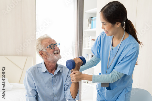 Female nurse physical therapy elderly man at hospital ward. Asian female nurse caring elderly man patient. Hospital care and older adults concept photo