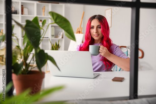 Beautiful woman with cup of tea using laptop at home