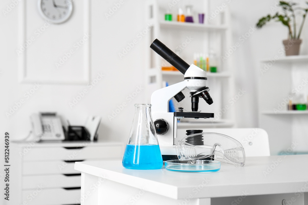 Modern microscope and chemical glassware on table in medical laboratory Modern microscope and chemical glassware on table in medical laboratory
