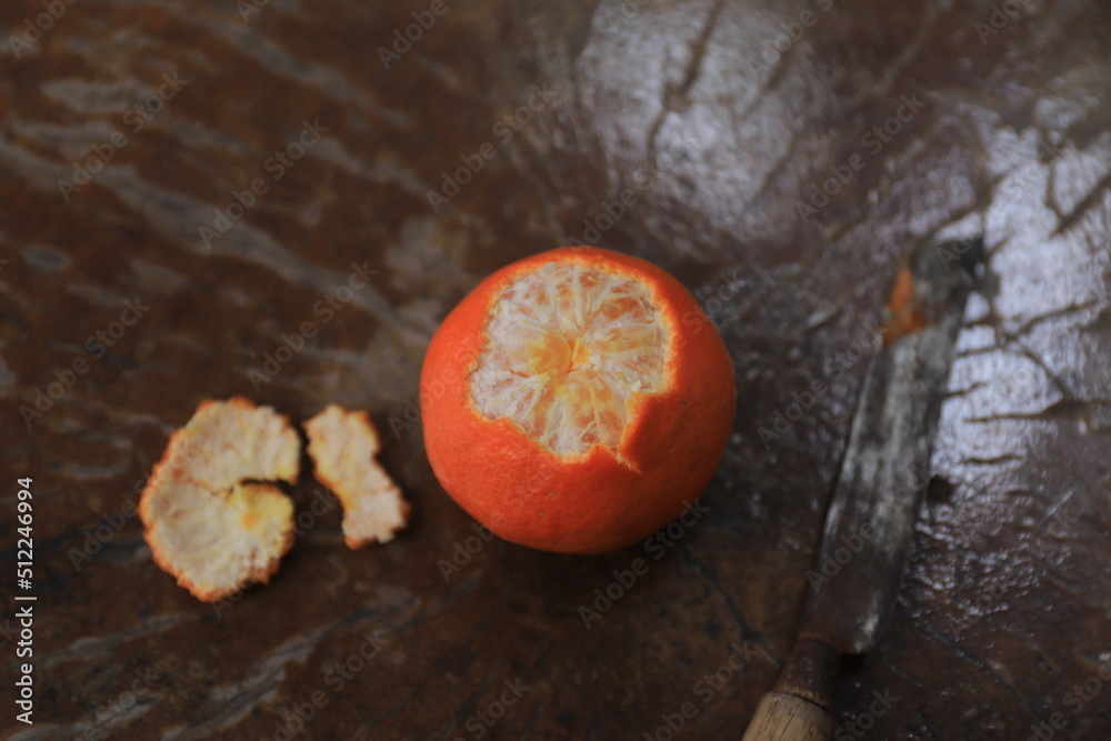 Fresh orange, partially peeled, on a wooden table