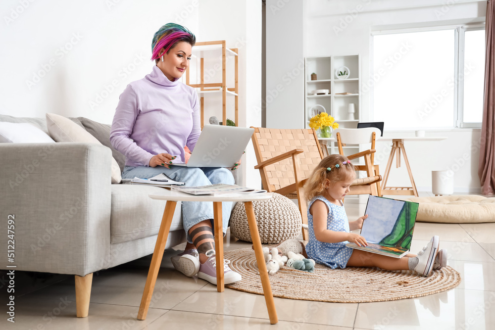 Little girl with book and her working mother at home Little girl with book and her working mother at home