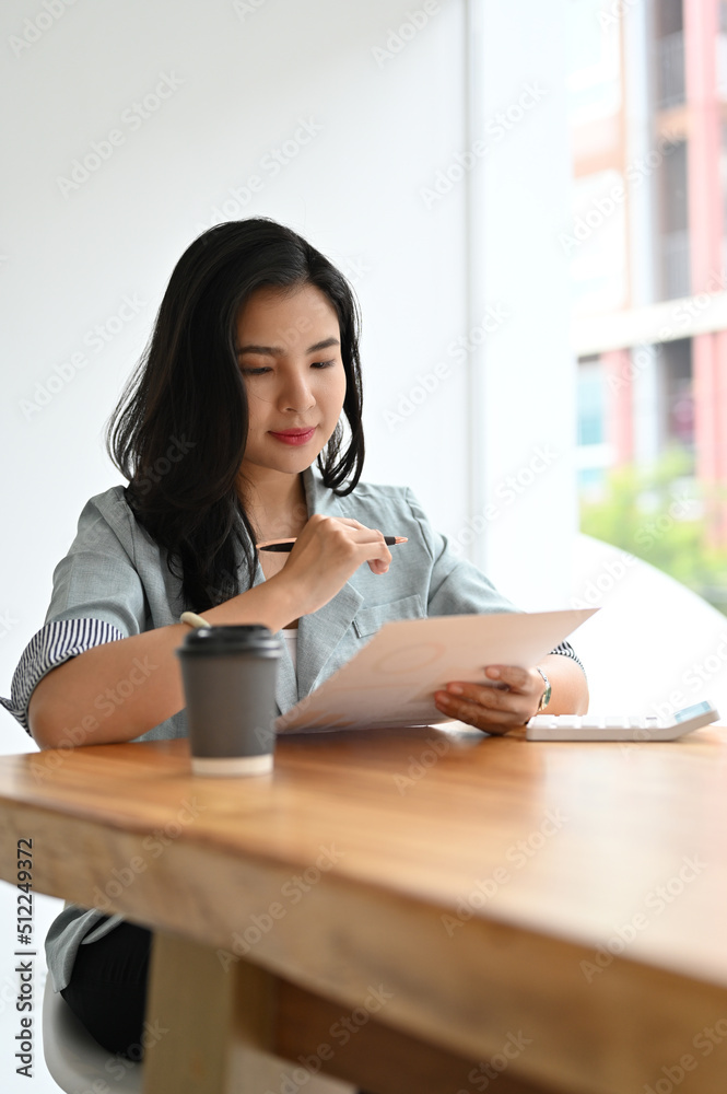 Professional young asian businesswoman reviewing a business proposal report Professional young asian businesswoman reviewing a business proposal report