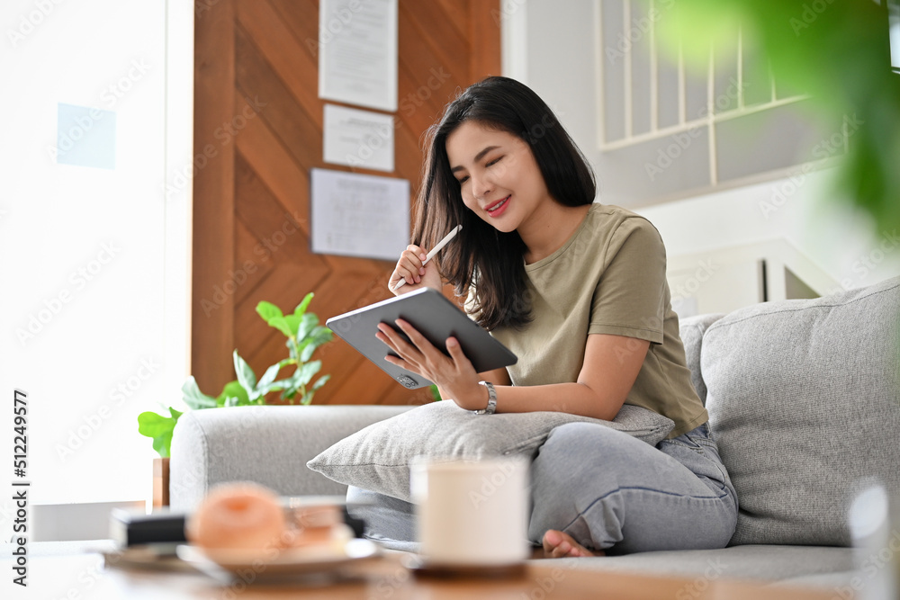 Beautiful young asian woman relaxes in the living room using digital tablet. Beautiful young asian woman relaxes in the living room using digital tablet.