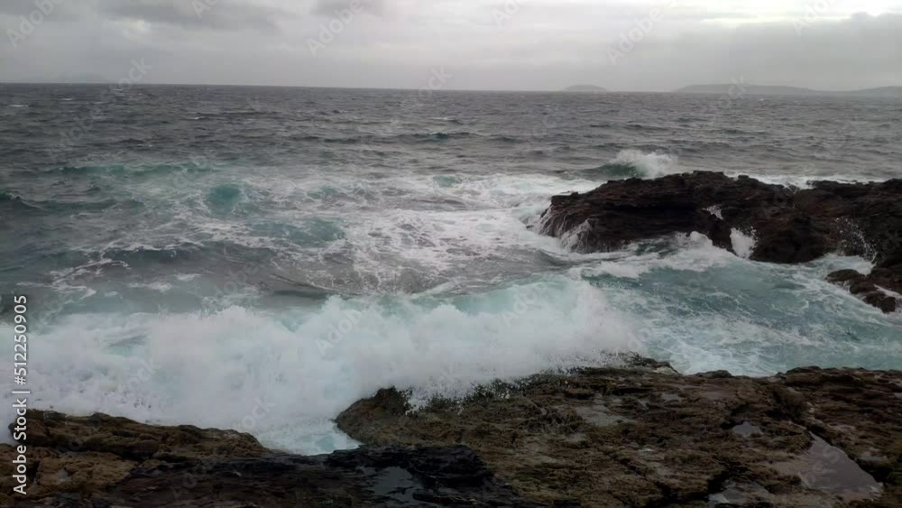 the sea on a windy and cloudy day with waves frothing against the rocks, dark storm clouds. Slow motion, shot view by turning right. Pontevedra, Galicia, Spain. the sea on a windy and cloudy day with waves frothing against the rocks, dark storm clouds. Slow motion, shot view by turning right. Pontevedra, Galicia, Spain.