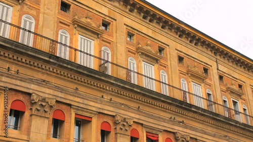 Low angle shot of ancient mullioned windows of the Palazzo Accursio, town hall in downtown of Bologna in Italy on a cloudy day. photo