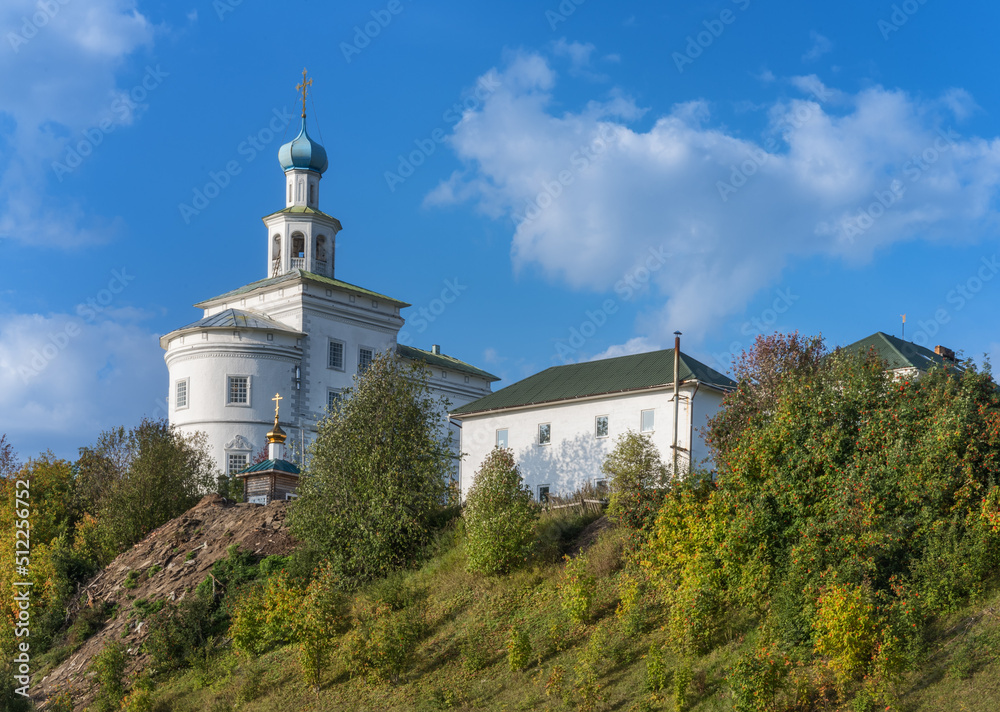 An ancient white monastery on a high mountain against a blue cloudy sky in summer. Cherdyn (Northern Ural, Russia).