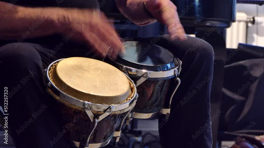 A man plays the bongo drums. 