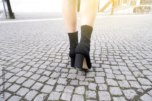High heel shoes boots woman on the street walking. Fashion female legs in leather black footwear.