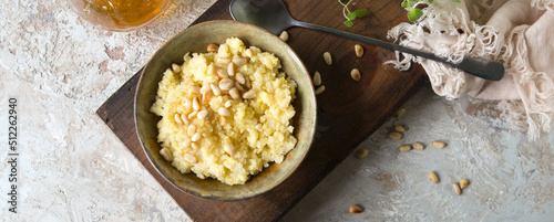 a bowl of millet porridge with honey and pine nuts on the table