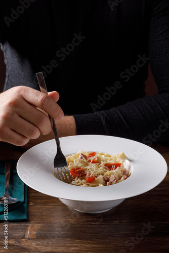 Person eating pasta in restaurant. No face