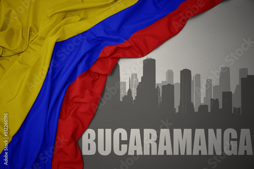abstract silhouette of the city with text Bucaramanga near waving national flag of colombia on a gray background. photo