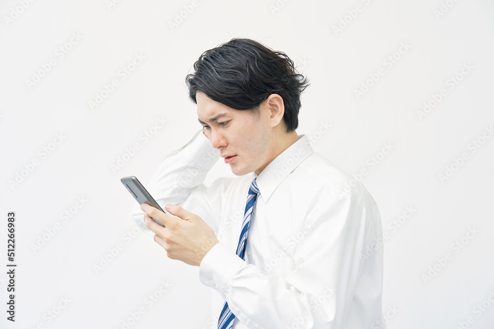 スマホを見て頭を抱えるビジネスマン 白背景 スマホを見て頭を抱えるビジネスマン 白背景