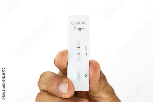 Hand showing Covid-19 self antigen rapid test kit with positive result on white background