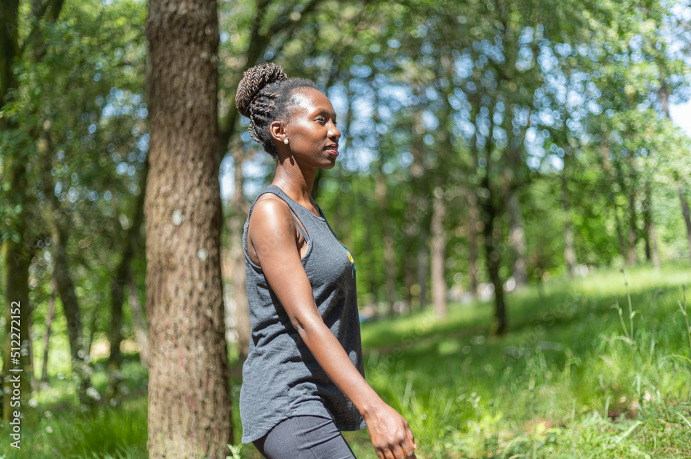 Naklejka premium Young woman hiking, walking in the woods on a sunny day