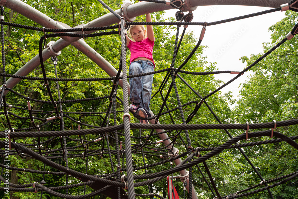 Happy teenager girl child playing in rope spider web at playground. Children. High quality photo Happy teenager girl child playing in rope spider web at playground. Children. High quality photo