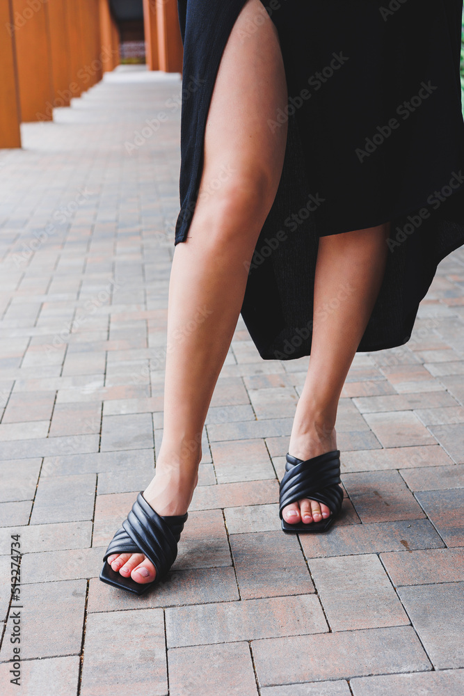 Smooth beautiful slender legs of a girl in black high-heeled sandals on the floor against a gray parquet floor. flawless epilation and tanning, personal care, female beauty Smooth beautiful slender legs of a girl in black high-heeled sandals on the floor against a gray parquet floor. flawless epilation and tanning, personal care, female beauty