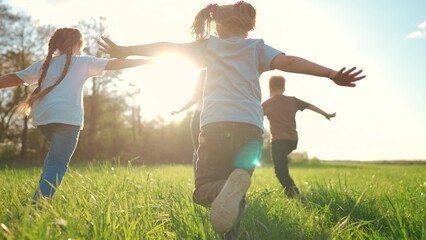 kids run in the park. a large group of a team of children running back view sunlight in the summer on the grass in lifestyle the park camera movement. people in the park happy family kid dream concept