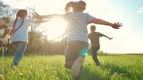 kids run in the park. a large group of a team of children running back view sunlight in the summer on the grass in lifestyle the park camera movement. people in the park happy family kid dream concept