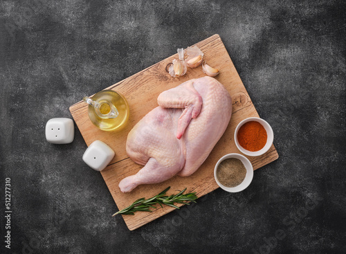 Fresh half of raw chicken with spices and seasonings on a wooden board. photo
