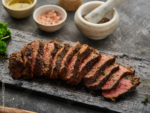 Grilled sliced beef steak on cutting board over grey table. Beef tenderloin steak. Filet Mignon recipe. photo