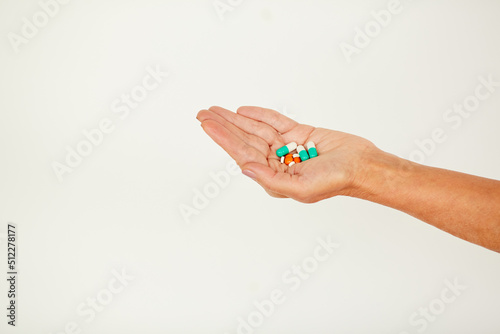 Close-up of unrecognizable person holding handful of various pills and antibiotics against white background