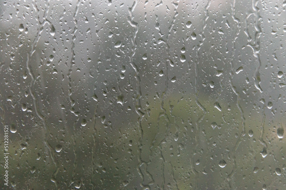 Raindrops drip down on the window glass. Soft selective focus.