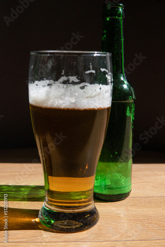beer in a glass near a green bottle and on a black background
