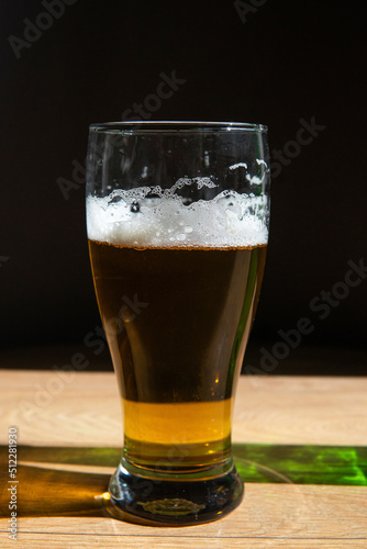 beer in a glass near a green bottle and on a black background