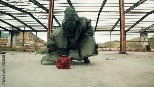 Soldier leans bunch of red flowers on the ground
