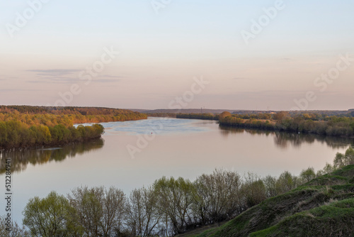 Evening landscape. Cloudy May day. Clouds are reflected in the lake. Peaceful landscape on the banks of the reservoir. Relax in nature. © Sergei