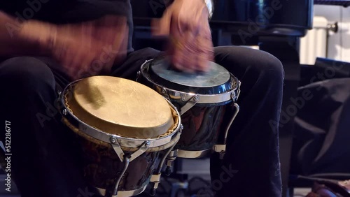 A man plays the bongo drums.  photo