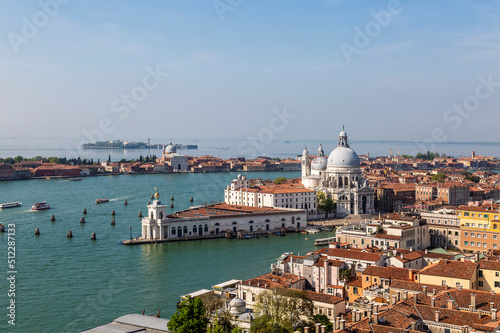 Top view of Venice with urban buildings, the Cathedral of Santa Maria della Salute and canals with tourist ships sailing through them. Italy
