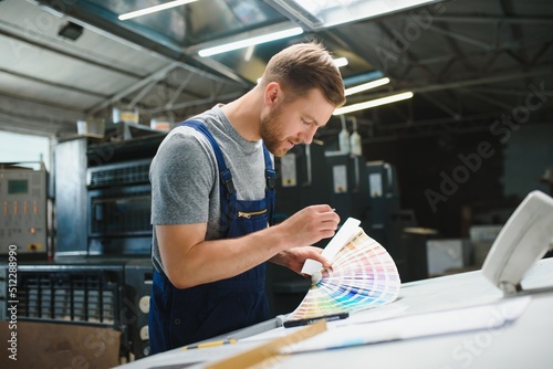 Man worker measuring printing color with spectrometer on the operating desk of the printing plant photo