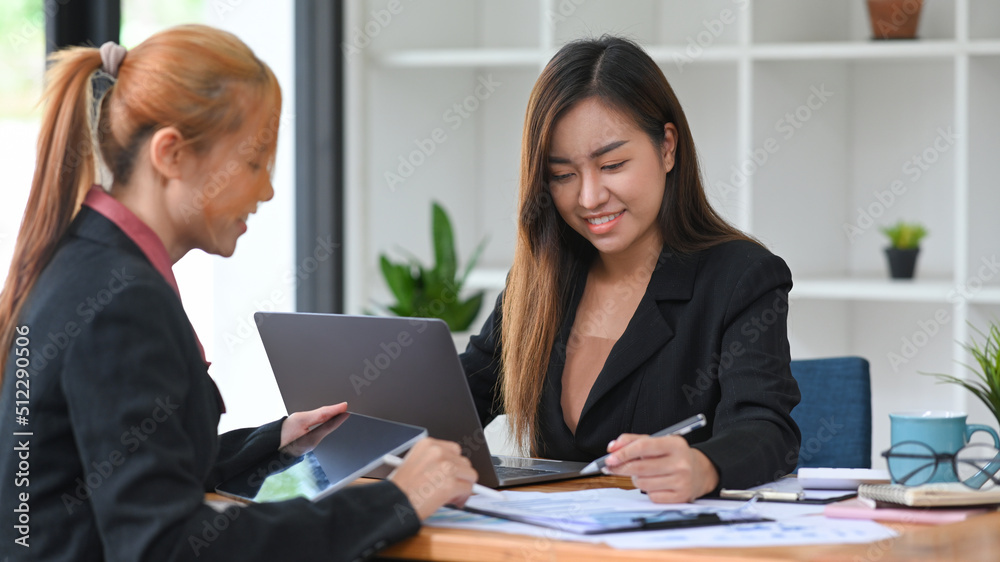 Two happy young business colleagues working with financial reports together Two happy young business colleagues working with financial reports together