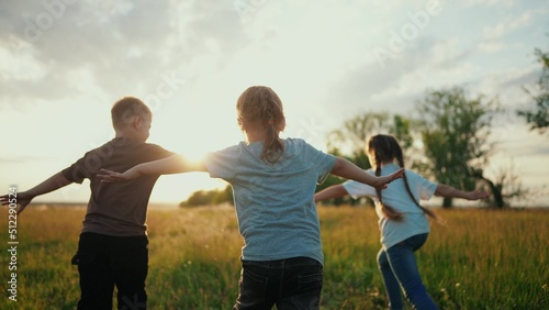 kids run in the park at sunset. happy family children camp kid dream concept. a group of children run on the grass at sunset the rays of the sun silhouette. childhood dream teamwork fun concept