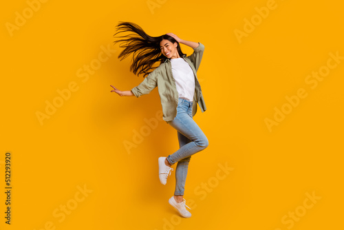 Full size portrait of overjoyed pretty person jumping flying hair isolated on yellow color background