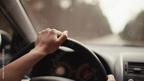 Close-up of a girl holding her hand on the wheel in a car. A woman driving a car goes on a trip.