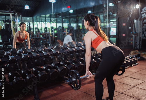 The back side of Asian woman athlete exercising with heavy weights at cross training gym.