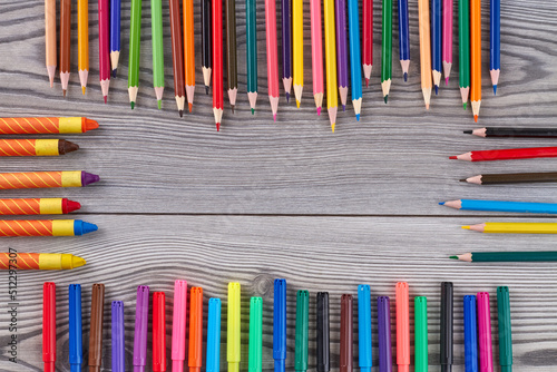 Frame of many colorful pencils and crayons with copy space. Grey wooden desk. Top view flat lay. photo
