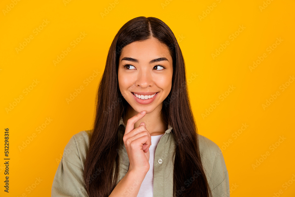Portrait of minded cheerful girl finger touch chin look interested empty space isolated on yellow color background Portrait of minded cheerful girl finger touch chin look interested empty space isolated on yellow color background