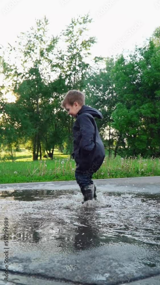 Boy in rubber boots jumping in a puddle Boy in rubber boots jumping in a puddle