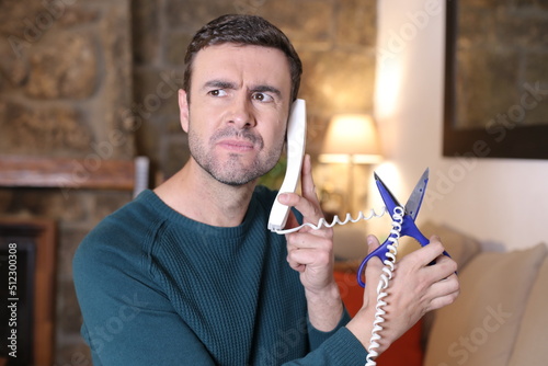 Fotótapéta Irritated man cutting telephone cord with scissors