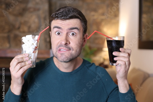 Man comparing soft drink with sugar cubes photo