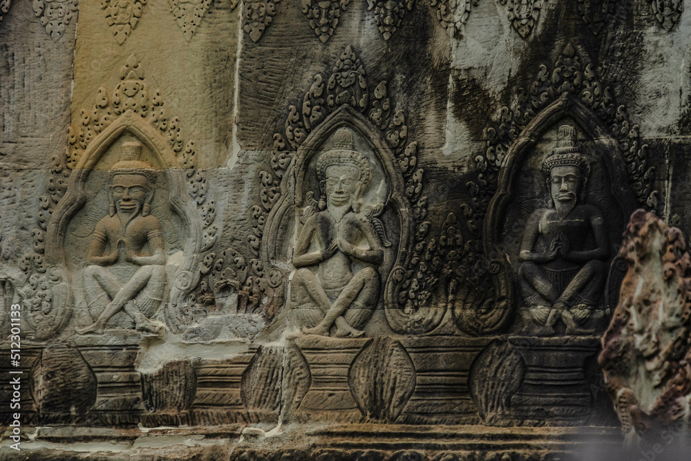 A sandstone wall carving depicting a hermit sitting with hands on her knees in Angkor Wat, Siem Reap, Cambodia.