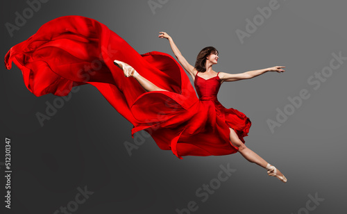 Ballerina Dance. Ballet Dancer in Red Dress jumping Split. Woman in Ballerina Shoes dancing in Silk Gown flying on Wind over Gray Studio Background